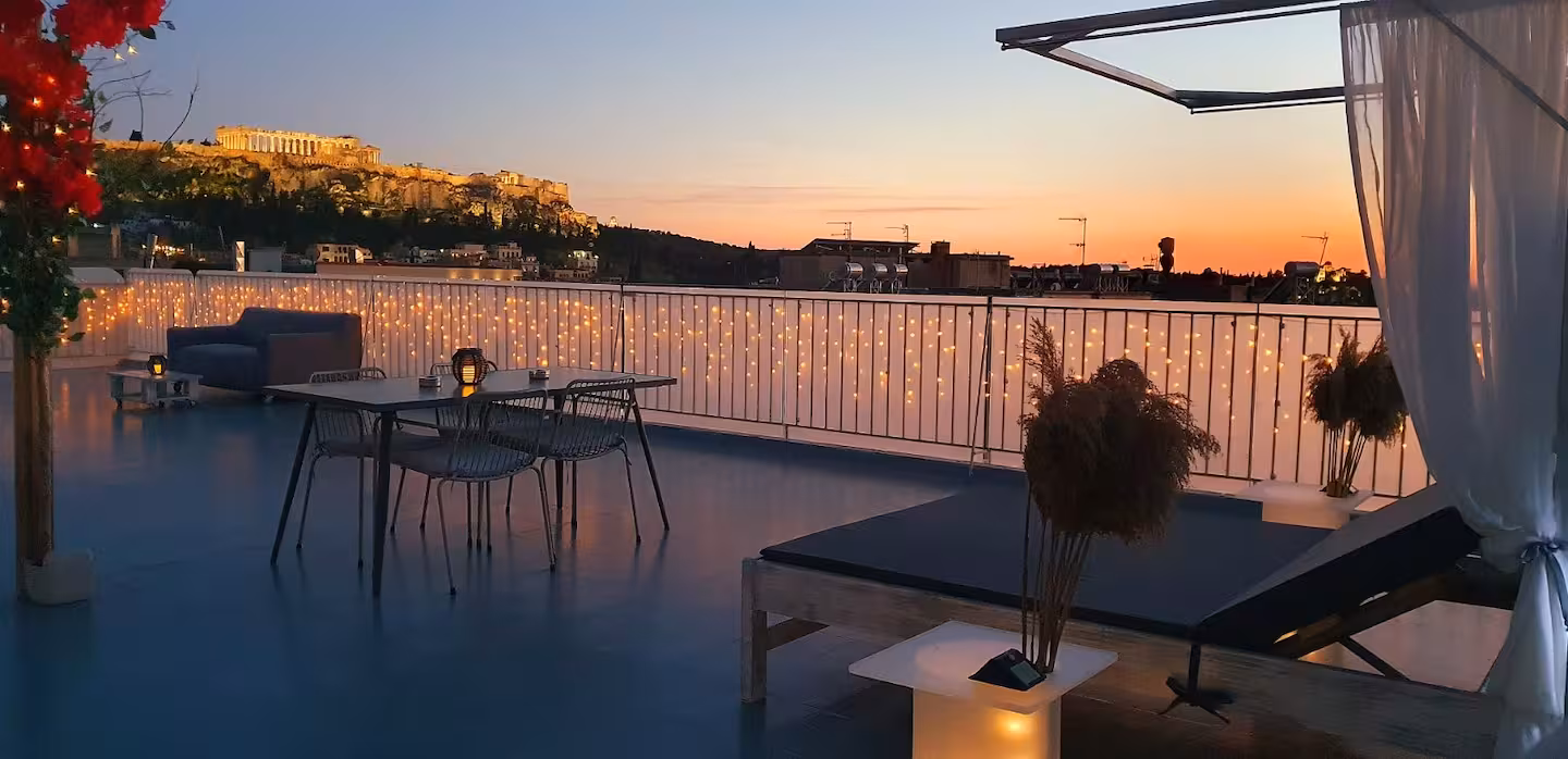 Panoramic rooftop terrace at sunset with dining table and lounge seating