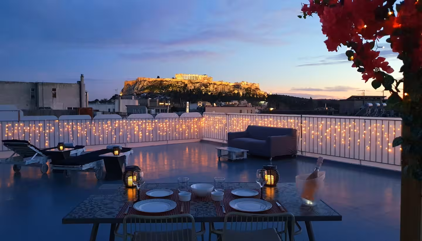 Rooftop dining table set for two at sunset with the Acropolis on the horizon