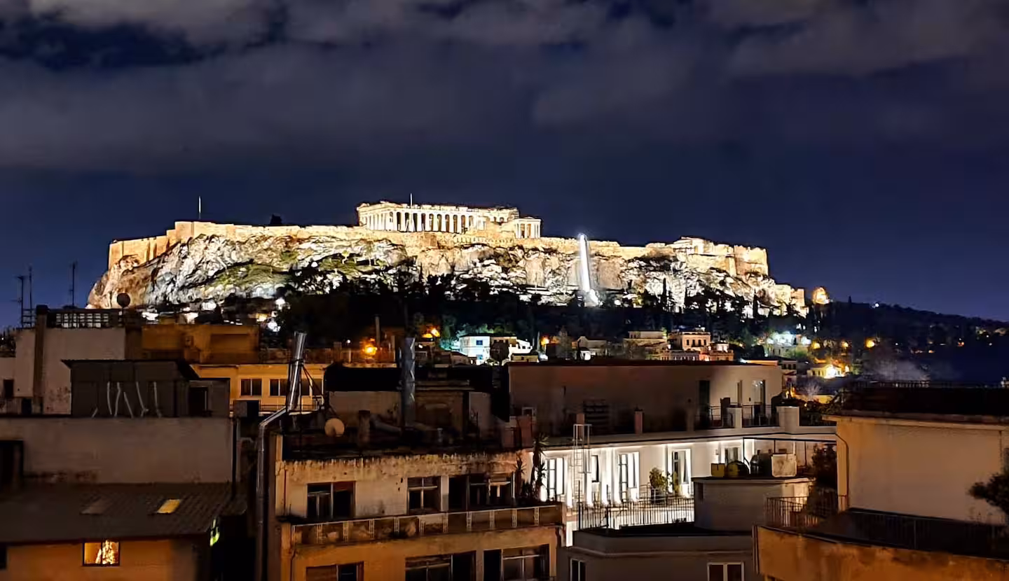 Close-up night view of the illuminated Acropolis above the Athens rooftops